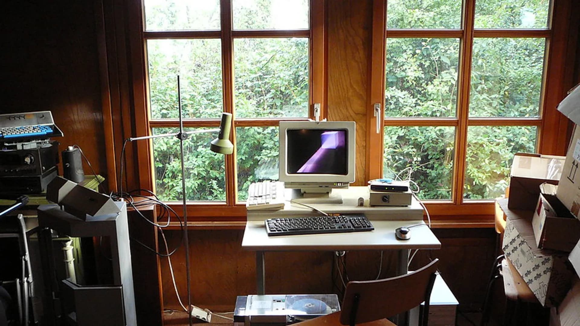 A home Wi-Fi router on a wooden desk beside a laptop showing a network connection screen.