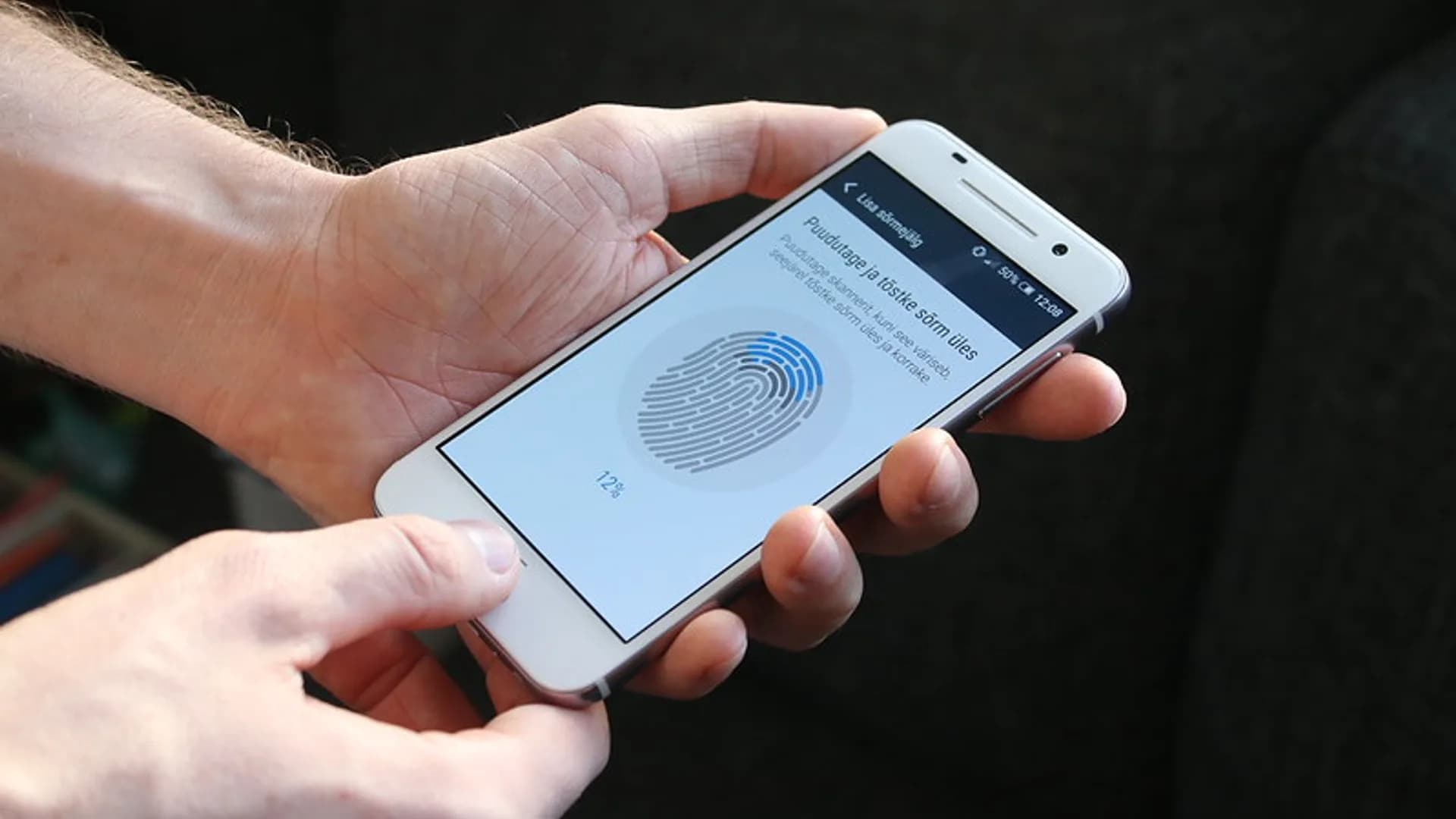 A person unlocking a smartphone with a fingerprint to sign in without typing a password