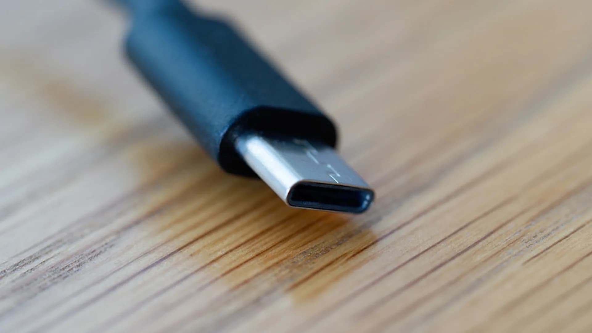 Assorted USB-C cables and a charger on a desk, showing different power and data ratings
