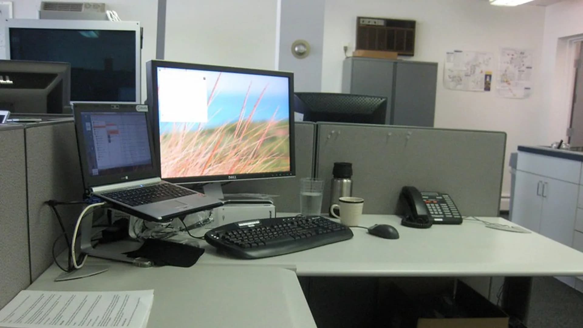 A smartphone connected by USB cable to a laptop on a desk, syncing a backup